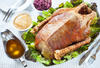 Roast goose with lettuce, red cabbage and applesauce on metal plate, on a gray tablecloth, horizontal