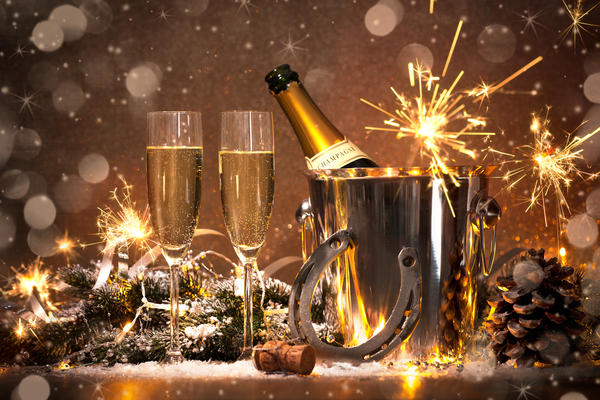 New Years Eve celebration background with pair of flutes and bottle of champagne in bucket and a horseshoe as lucky charm