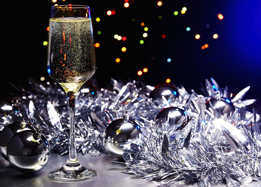 A New Year's Eve scene with champagne glasses and Christmas lights in the background.