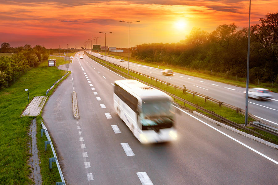 White bus in the rush hour on the highway at dusk