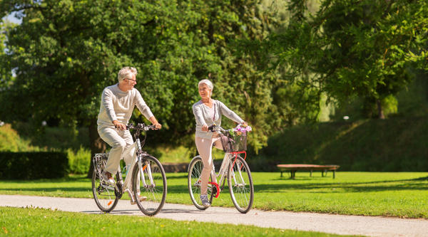 active old age, people and lifestyle concept - happy senior couple riding bicycles at summer park